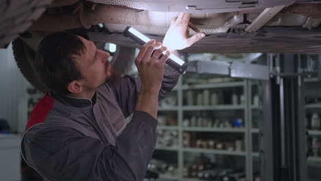 A-man-foreman-inspects-the-exhaust-system-of-a-car